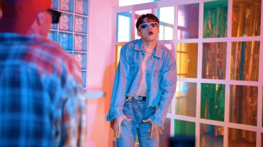 Ortasında dans eden profesyonel mutlu hipster onu alkışlayan çeşitli arkadaşlarıyla dans ediyor. Çekici Asyalı kırığı gece kulübünde neon ışığıyla enerjik adımlar atıyor. Mutluluk.