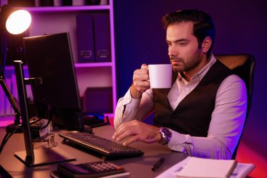 Gülümseyen zeki işadamı, elinde kahve fincanı olan satış ekibiyle buluşuyor ve geceleri Mor Neon Light Home Office 'deki bilgisayar ekranında ürün hedef pazarını araştırıyor. Tahmin et..