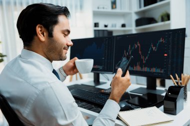 Elinde telefon dinamiğine odaklanan kahve fincanı tutan borsa yatırım ekranı veri analizini karşılaştırarak iç işlerinde yüksek kârlı finans teknolojisi pazarına yatırım yapıyor. Tahmin et..