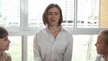 Farklı öğrencilerle çevrili yerde birlikte otururken, zeki beyaz bir öğretmen ders veriyor. Çok kültürlü bir öğrenciyle oynayan profesyonel bir eğitmen. Yaratıcı eğitim konsepti. Etkinlik.