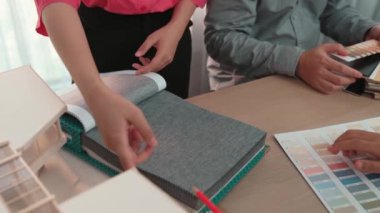 Mimari ekipman kullanarak yavaş çekim ev tasarımcısı bir plan çizerken, iç mimari tasarımcı da müşterilerin talebine göre renk örneklerinden uygun renkler seçiyor. Değiştirilmiş