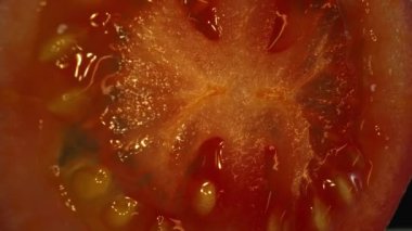 Dilimlenmiş domatesin makro fotoğrafı. Domates eti sulu ve yumuşak görünüyor, hafif bir sertlikle. Dilimlenmiş domates ışığın altında parlıyor, tazeliklerini ve olgunluklarını gösteriyor. Geliştirilebilir.
