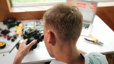 Elektronik ekipman ve dizüstü bilgisayar görüntüleme programı olan mutlu öğrenci çalışma arabası modeli inşaatının üst görüntüsü STEM sınıfında dağılıyor. Yaratıcı eğitim. Öğretim
