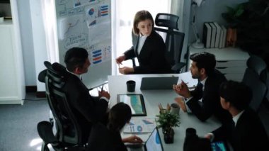 Akıllı yönetici yöneticisinin üst görünümü, beyaz tahtayı işaret ederken çeşitli takımlara satışların arttığını gösteriyor. Bir grup insan borsa yatırım verilerini analiz ediyor. Zaman aşımı. Müdürlük.