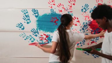 Küçük çocukların el kaplamalarını renkli ve boyalı duvarlarla çiziyorlar. Sanat dersinde kırmızı ve maviyle boyanmış boya odasıyla karışık ırk tutma tepsisiyle lise öğrencisi. Yaratıcı aktivite. Öğretim