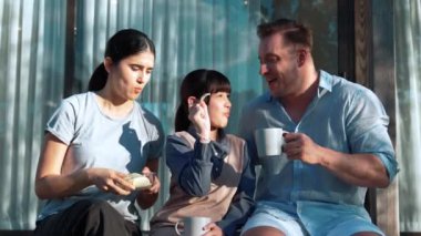 Güzel bir evlilik çifti ve kızı açık terasta yemekli piknik yapıyorlar. Açık hava aktivitelerini kullanan aile, çocuk ve güçlü aile bağı veya ilişkisinin gelişmesini desteklemek için sevgiyi gösterir. Uyumsuzluk.