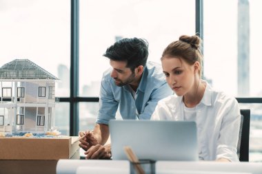 Genç yetenekli proje yöneticisi, modern ofis veya mimarlık stüdyosundaki proje planını kullanarak, Kafkas mühendisi ev modunu incelerken dizüstü bilgisayar kullanarak çalışıyor. İnşaat mühendisliği, yaratıcı tasarım. İzleme.