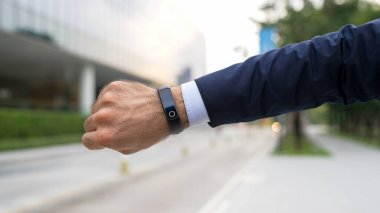Profesyonel iş adamının yakın çekimi akıllı saat ve zamanı gösteriyor. Profesyonel patron, genel müdür, şehir manzarası ile zamanı kontrol eden bir lider. İş için. Arka plan bulanık. Sevinçli..
