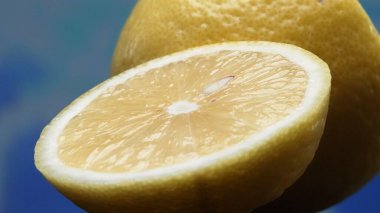 A slice of fresh lemon, bright yellow and vibrantly citric, lies exposed. The flesh, glistening with refreshing juice, reveals its segmented interior. The essence of citrus vibrancy. Comestible. clipart