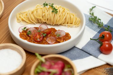 Lezzetli yiyecekler, ev yapımı spagetti, kıymalı domates sosu ve fesleğen fırlatma elementleri, şef masası dekoratif baharatlarla servis ediliyor. Varsayım.