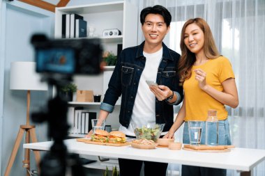 Aşçılar, sosyal medya yemek programı kanalı canlı yayın menü yemeği salatası, kepekli çörek ve video kameradan hamburger kaydı için telefonda yorum okuyorlar. İnfobahn.