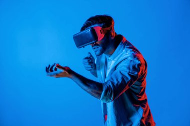 VR cam takan ve hareket eden el kol tabancası tutan bir adamın yan görüntüsü. Oyuncu, gelecekteki sanal gerçeklik kulaklığını ya da gelecekteki yenilikleri kullanarak meta dünyaya giriyor ya da aksiyon oyunu oynuyor. Sapma.