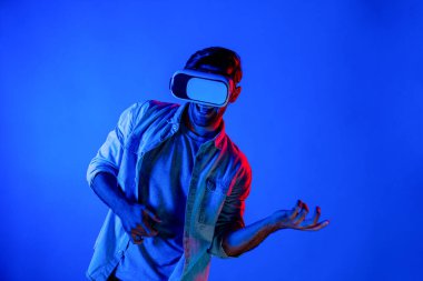 Beyaz adam hareket ediyor, gitar çalıyor ve arka planda ışık yansıması olan bir VR cam takıyor. Oyuncu metaevren ya da sanal gerçeklik programına teknolojik yenilikler kullanarak girer. Sapma.