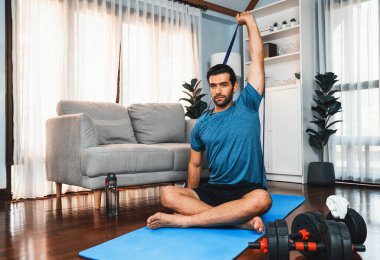 Atletik ve sporcu adam, evdeki formda fizik ve sağlıklı spor yaşam tarzı için egzersiz yaparken direnç bandı egzersizi yapıyor. Gaiety ev egzersizi antrenman konsepti.