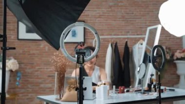 Kadın nüfuzlu kişi sosyal medya ya da blog için canlı yayın yapan video klip eleştirmeni derisini çekiyor. Canlı kozmetik stüdyosu ışıklandırması olan mutlu genç bir kız pazarlama için internet üzerinden yayın yapıyor..