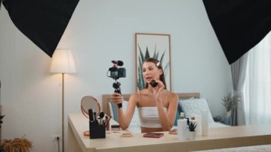 Sosyal medya için güzellik ve kozmetik video içeriği hazırlayan genç bir kadın. Güzellik blogcusu kameraya gülümserken seyircilere ve takipçilere güzellik bakımını gösteriyor. Düzenle