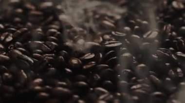 Kahve çekirdeği yığınından çıkan kavrulmuş dumanla taze kahve çekirdeğini kapat. Kokulu ve kokulu sıcak dumanlı sıcak kahve çekirdeğinin makrografisi fasulye yığınından gelir. Yukarıdan aşağıya doğru. Geliştirilebilir.