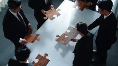 İş adamlarının toplantı odasında yapboz yapmaları. Profesyonel pazarlama ekibi yapboz parçalarını toplarken masada duruyor. Birlik, işbirliği ve ekip çalışmasını göster. Müdürlük.