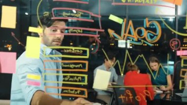 Cam duvarda istatistiksel mali grafiği olan pazarlama stratejisini işaret eden yetenekli bir işadamı. Profesyonel iş ekibi sunumu dinlerken müdür pazarlama fikrini paylaşıyor. İzleme