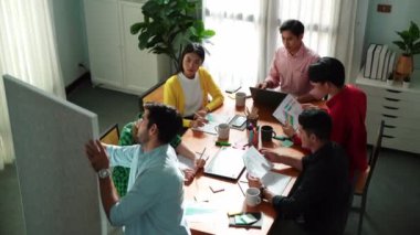 Çekici iş adamlarının en iyi görüşü pazarlama planını sunarken, çeşitli yatırımcılar yaratıcı fikirleri dinliyor ve finansal istatistik belgelerini okuyorlar. Toplantıda fikir paylaşan bir grup insan. Cemaat.