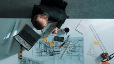 İş kadınının proje planı, ekipman ve güvenlik kaskıyla toplantı masasında oturan mühendis el planının en üst görüntüsü. Yöneticinin hava görüntüsü bina inşaatını açıklıyor. Hizalama.