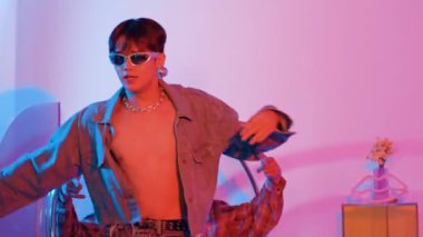 Asyalı sokak dansçısının neon ışıkla pop müziğe geçişine yakın çekim yaparken çeşitli arkadaşlar oturuyor ve performansı destekliyor. Profesyonel sanatçı stüdyoda dans figürleri yapıyor. Mutluluk.