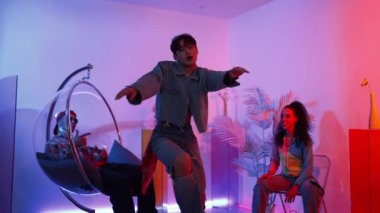 Çok kültürlü bir arkadaş kürsüde otururken Asyalı yetenekli bir dansçı modern müziğe geçiyor. Profesyonel dansçı, hipster takımı tezahürat yaparken ve desteklerken enerjik adımlar atıyor. Mutluluk.