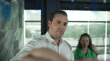 Yetenekli işadamı, cam duvara renkli yapışkan notlar yapıştırarak proje yöneticisine pazarlama fikrini sundu. Proje yöneticisi yatırımcıya projeyi gösteriyor, anlatıyor, gösteriyor. Yönlendirici.