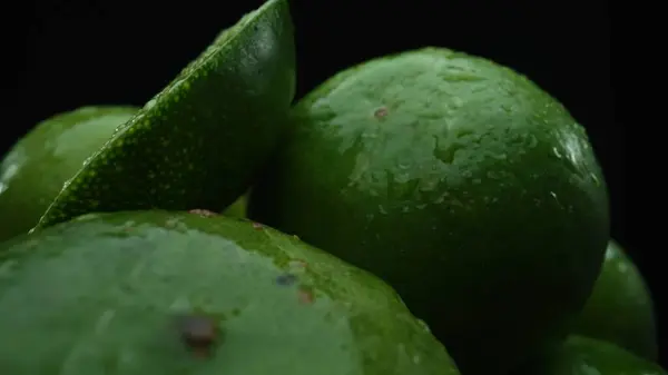 stock image Slices of lime are meticulously arranged in a pile, set against a black background. Each lime slice is captured in stunning detail, its vibrant green hue and enticing texture. Close up. Comestible.