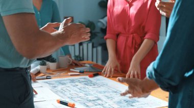 İnşaat mühendisi ekibinin renkli paletlerle toplantı masasında plan yazışının en üst görüntüsü. Yönetici proje planlarına bakarken bir grup zeki insan plan yapıyor ve not alıyor. Sempozyum.