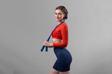 Vücut uzunluğunun tamamı atletik ve sportif genç bir kadın tarafından izole edilmiş arka planda ip atlarken çekildi. Sağlıklı aktif ve vücut bakımı yaşam tarzı.