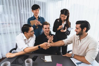 Çeşitli ofis çalışanları stratejik iş pazarlama toplantısı üzerine anlaşma yaptıktan sonra el sıkışıyor. Takım çalışması ve olumlu tutum verimli ve destekleyici bir iş yeri yaratır. Tedbirli