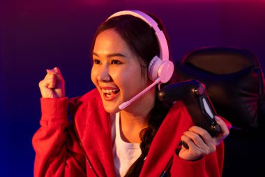 Neon odada kulaklık takan yetenekli Esport takım oyuncularını yumruklayarak oynayan güzel Asyalı kız flamasının sunucu kanalı. Taktik.