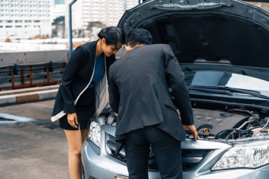 Erkek kadına araba sorununu çözmesi için yardım eder. Hasarlı parçayı tamir etmek için arabanın kaputunu açtı. uds