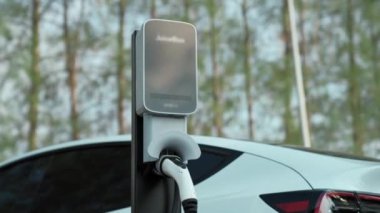 EV elektrikli araç EV şarj istasyonu ulusal park veya açık hava orman manzaralı. Sonbahar mevsimi ormanlarında çevre dostu EV arabalarla doğal koruma. Yükselt
