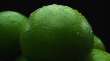 Limon dilimleri titizlikle bir yığın halinde, siyah arkaplana göre dizilmiş. Her bir kireç dilimi çarpıcı detaylar, canlı yeşil rengi ve baştan çıkarıcı dokusu ile yakalanır. Kapatın. Geliştirilebilir.