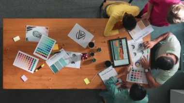 Proje yöneticisi renk paletleri seçerken tasarımcının tablete baktığı yukarıdan aşağıya hava görüntüsü. Profesyonel grafik tasarımının en üst görüntüsü ve logoya bakın. Yetenekli ekip grafikleri seçiyor. Sempozyum.