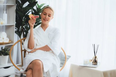 Güzellik ya da vücut bakımı güzellik salonu yaşam tarzı konsepti. Bornoz giyen bir kadın lüks otel kaplıcalarında ya da tatil odasında içkiyle rahatlıyor. Tatil ve boş zaman rahatlığı. Sessiz.