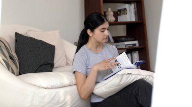 Kanepede oturan orta yaşlı bir kadın, sosyal ve teknolojik mesleki gelişmeler hakkında ders kitabı okur ya da zeki bir anne olmak için çocuk yetiştirir. Hayat boyu öğrenme konsepti. Uyumsuzluk.