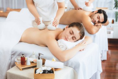 Sıcak bitkisel top spa masaj vücut tedavisi, masör nazikçe bitki torbasını çift müşteri vücuduna bastırıyor. Aromaterapi dinlenme sükuneti ve sükuneti kaplıca salonundaki atmosferi aydınlatıyor. Sessiz.