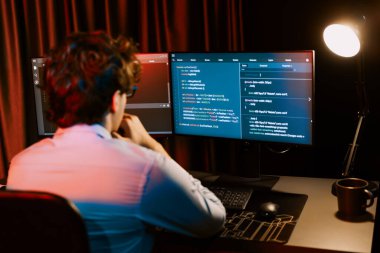 Uygulama pc ekranları ile çevrili çevrimiçi yazılım geliştirme bilgilerini yoğunlaştıran IT geliştiricisi, neon modern ofis evindeki web sitesinde yazılım için program yaratıyor. Toplayıcı.