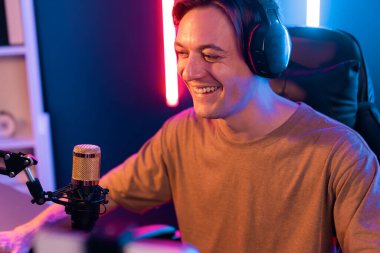 Oyun kanalı, online oyun oynayan akıllı flamalı oyun sunucusu, kulaklık takan, neon ışıklandırma odasındaki takım oyuncusuyla akıllı telefondan canlı yayında konuşan izleyiciler. Bireysel.