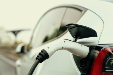 Kapalı EV şarj kolu fişe takıldı veya elektrikli arabaya bağlandı, EV araba aküsünü temiz çevre için sıfır CO2 emisyonu ile alternatif ve sürdürülebilir enerjiyle şarj etti. Kalıcı