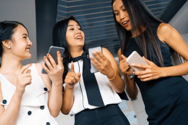 Üç kadın arkadaş ellerinde cep telefonuyla sohbet ediyorlar. Sosyal medya, dedikodu haberleri ve online alışveriş kavramı. uds