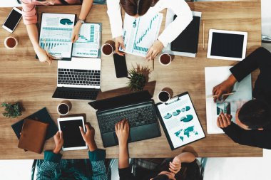 Modern ofisteki iş adamları ve iş kadınlarıyla grup toplantısındaki iş adamlarının en üst düzey görüşü, masada dizüstü bilgisayar, kahve ve belge ile. Kurumsal şirketler uds