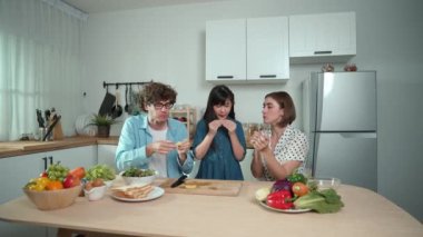 Modern mutfakta oturan ve meyve yiyen mutlu beyaz anne ve babalar. Enerjik aile birlikte vakit geçirerek meyve ya da mutfak gereçleri ve meyveli sağlıklı meyveler yemekten zevk alır. Pedagoji.