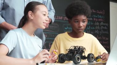 Kafkas öğretmeni dizüstü bilgisayarı işaret ederken araba modelleme sistemini kara tahtada kodlama veya programlama koduyla açıklıyor. Robot inşaatını öğrenen çeşitli öğrencileriniz kutlu olsun. Öğretim