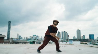 Profesyonel sokak dansçısının şehir manzaralı çatı katındaki dansçısının B-boy dans gösterisi. Çekici Asyalı hipster enerjik adımlar atıyor. Açık hava sporu 2024. Hiphop.