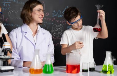 Laboratuvarda çalışan öğretmen, güvenlik gözlüğü takıyor, STEM sınıfında kimya bilimi üzerine deney yapıyor. Öğrenci komedisi tüpte sıvı deneyi yapar. Etkinlik.