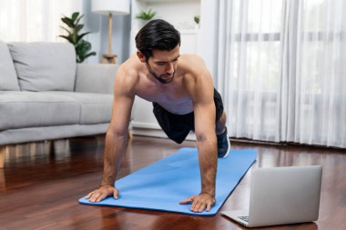 Atletik ve sporcu adam, evdeki fiziğe ve sağlıklı spor yaşam tarzına uygun vücut egzersizi sırasında spor minderinde şınav çekiyor. Gaiety evde egzersiz eğitimi.